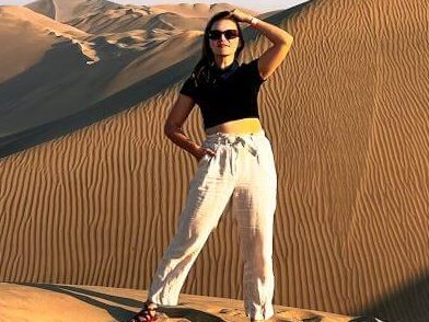 A woman poses in the sand dunes of the Peruvian desert.
