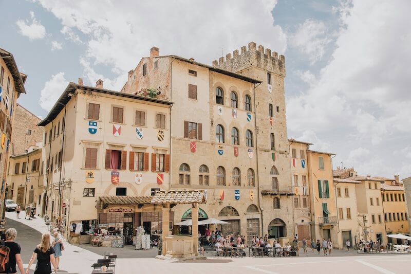 These Florence day trips include visits to nearby medieval villages like the one in the picture, depicting an ancient tower and winding roads, all within a few hours from the city.